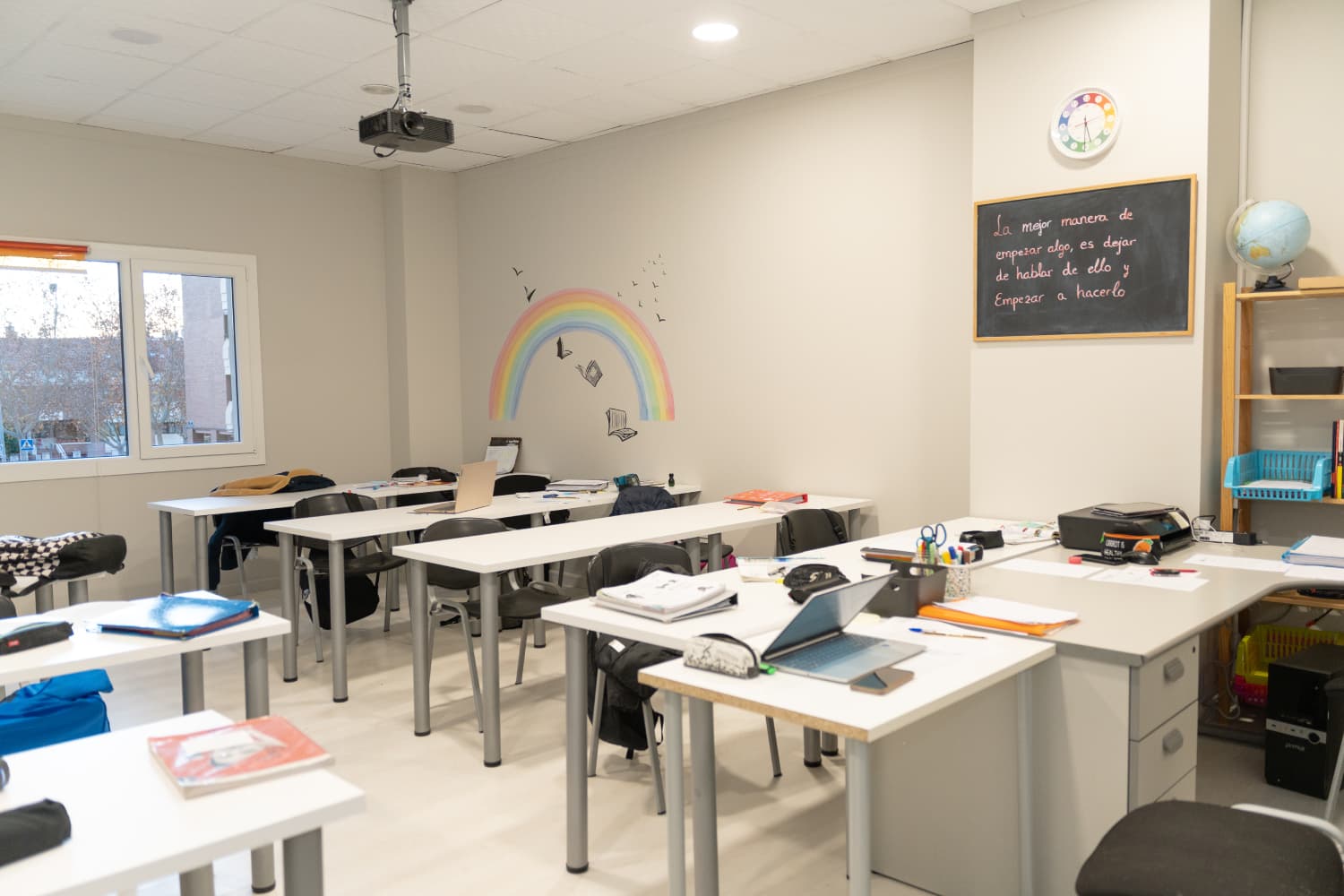 Aula del centro con mesas de estudio, pizarra y sillas preparadas para clase