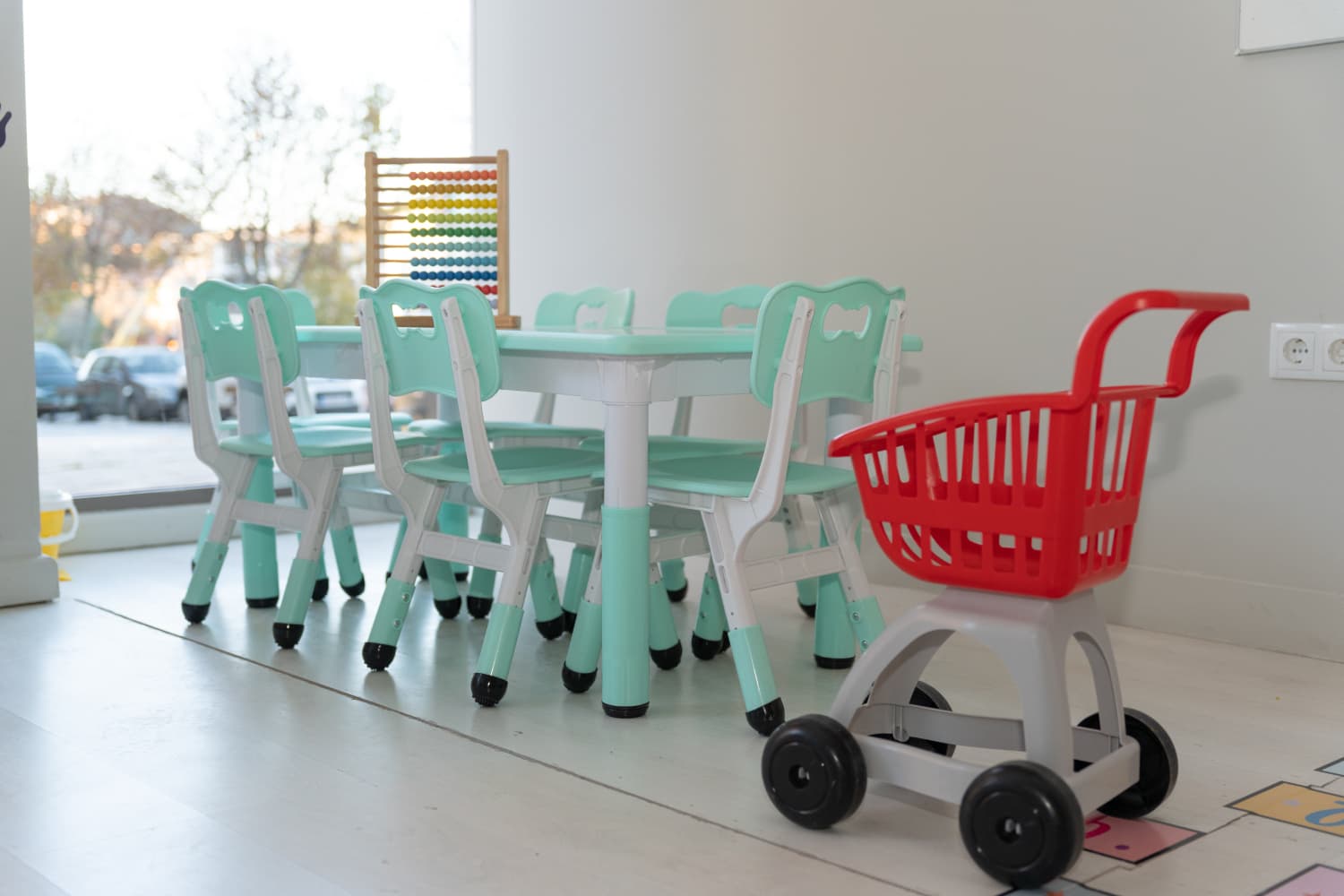 Rincón infantil con juguetes y mesas pequeñas para actividades educativas